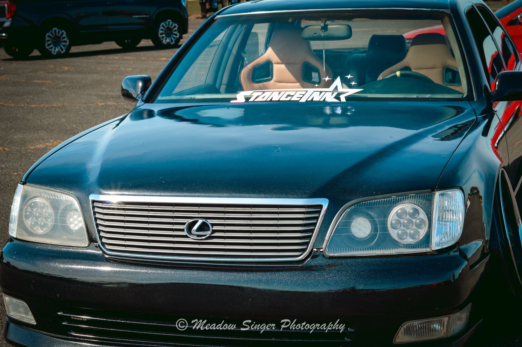 The front of a black Lexus sedan with a Stancenation windshield banner