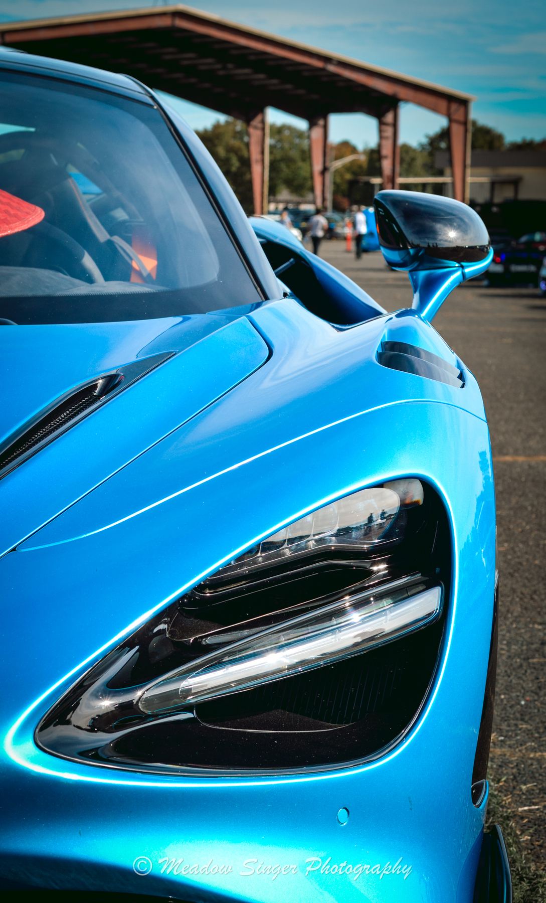 The headlight of a glossy blue supercar