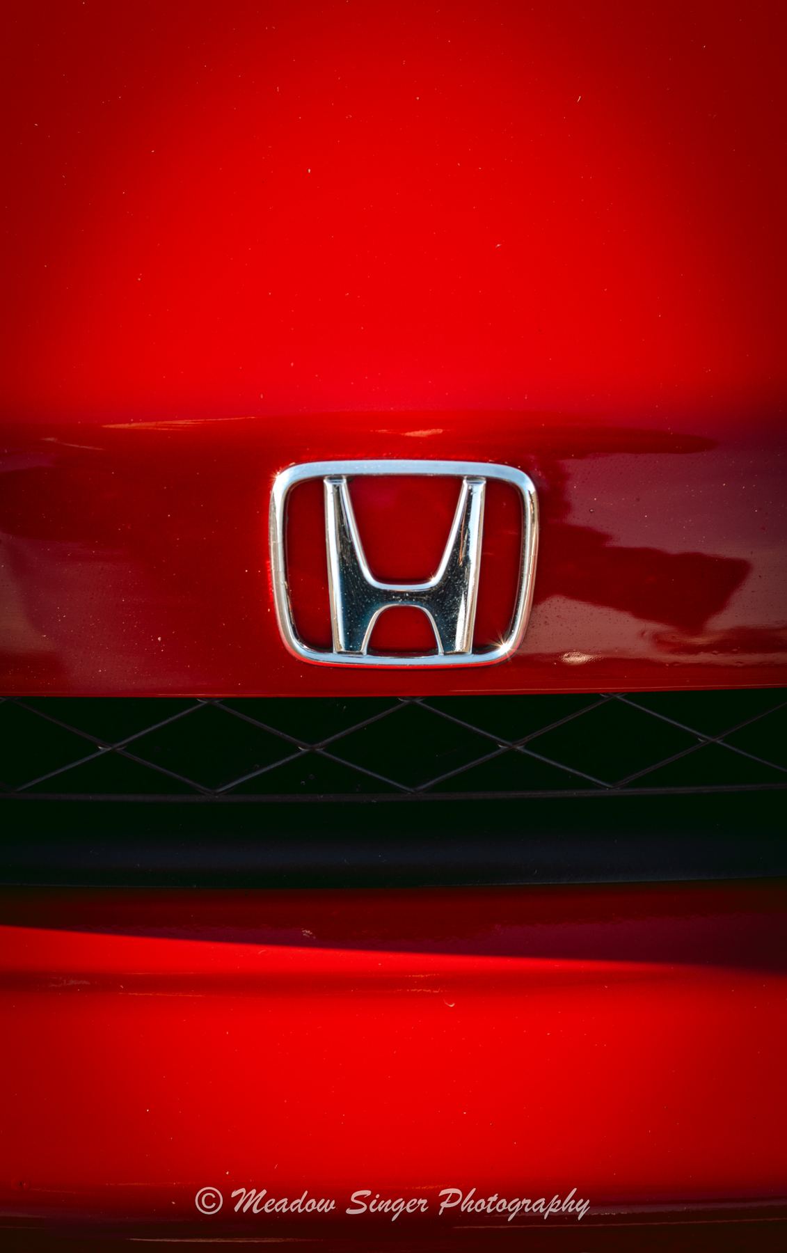 A chrome Honda badge on a red grille