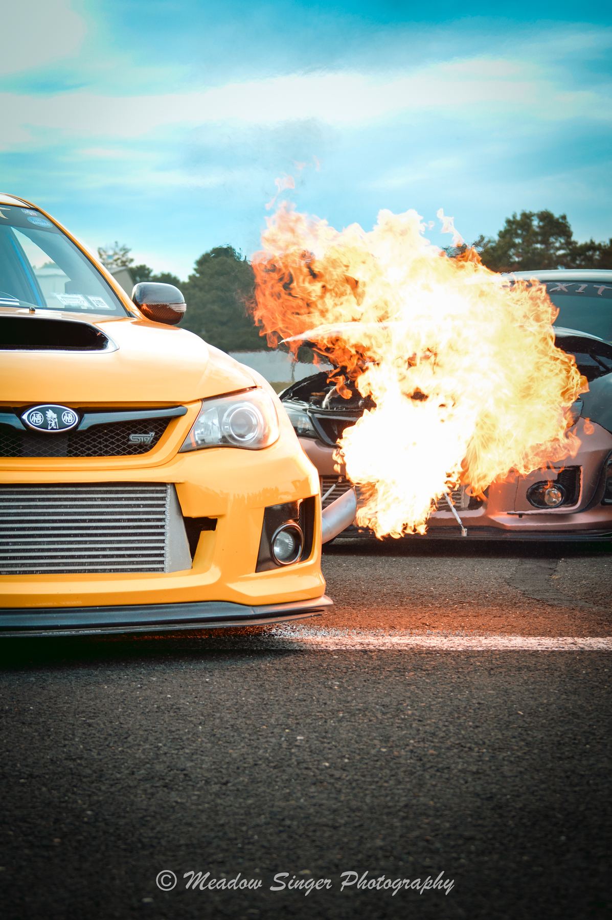 A yellow rally car with a fireball bursting behind it